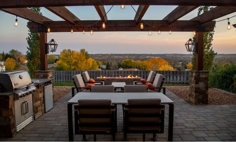 A patio with furniture placed and an arbor making up a sitting space